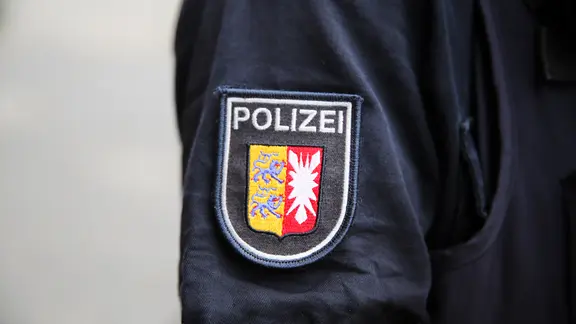 Schriftzug Polizei und Stadtswappen von Kiel stehen auf dem Ärmel an der Uniform eines Polizisten.