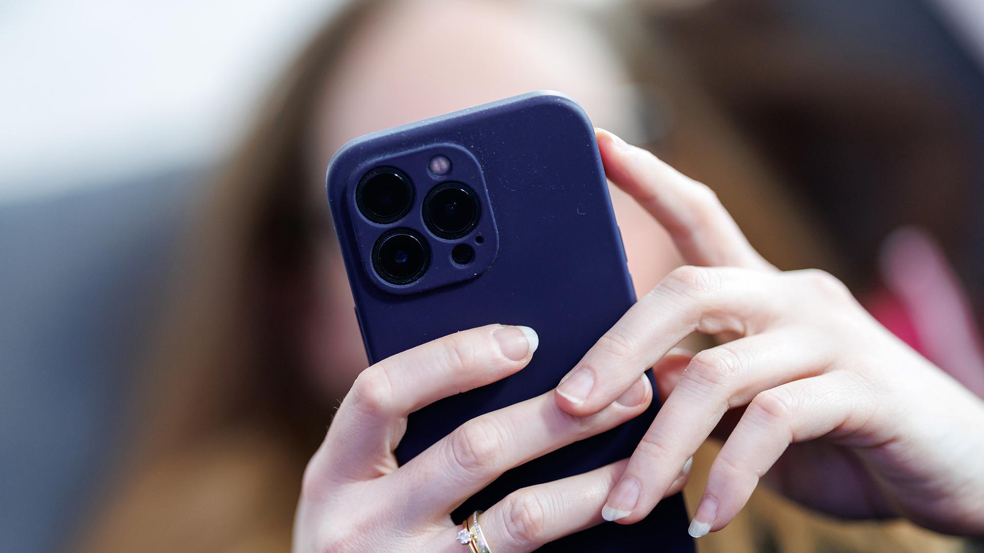 Eine junge Frau benutzt ein Smartphone. | picture alliance / dpa