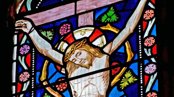 Ein farbiges Kirchenfenster zeigt Jesus Christus am Kreuz.