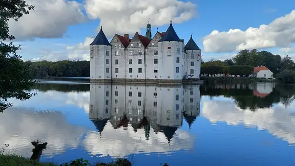 Das Schloss Glücksburg spiegelt sich im Wasser.