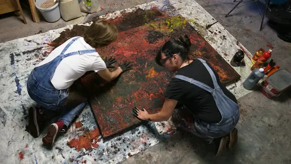 Von oben betrachtet: Marta Jansana und Frauke Kohlmorgen malen in ihrem Atelier gemeinsam. Das Bild liegt dafür auf dem Boden, die Künstlerinnen arbeiten mit ihren Händen, ohne Pinsel.
