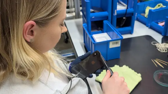 Eine Mitarbeiterin von Rebuy reinigt ein Smartphone.