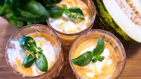 Melonensuppe mit Basilikum dekoriert in Gläsern serviert.
