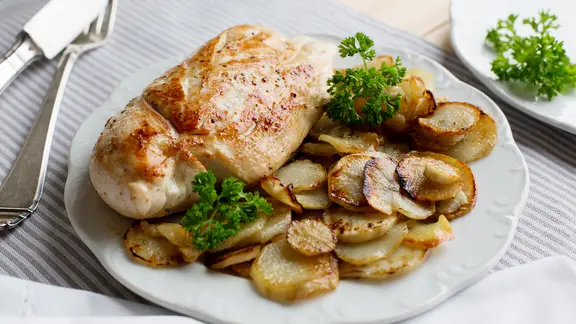 Hähnchenbrustfilet mit Topinambur auf einen Teller.