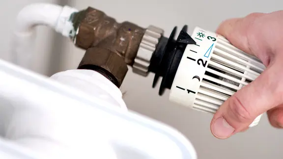 Eine Frau dreht am Thermostat einer Heizung. | picture alliance/dpa, Hauke-Christian Dittrich Eine Frau dreht am Thermostat einer Heizung.