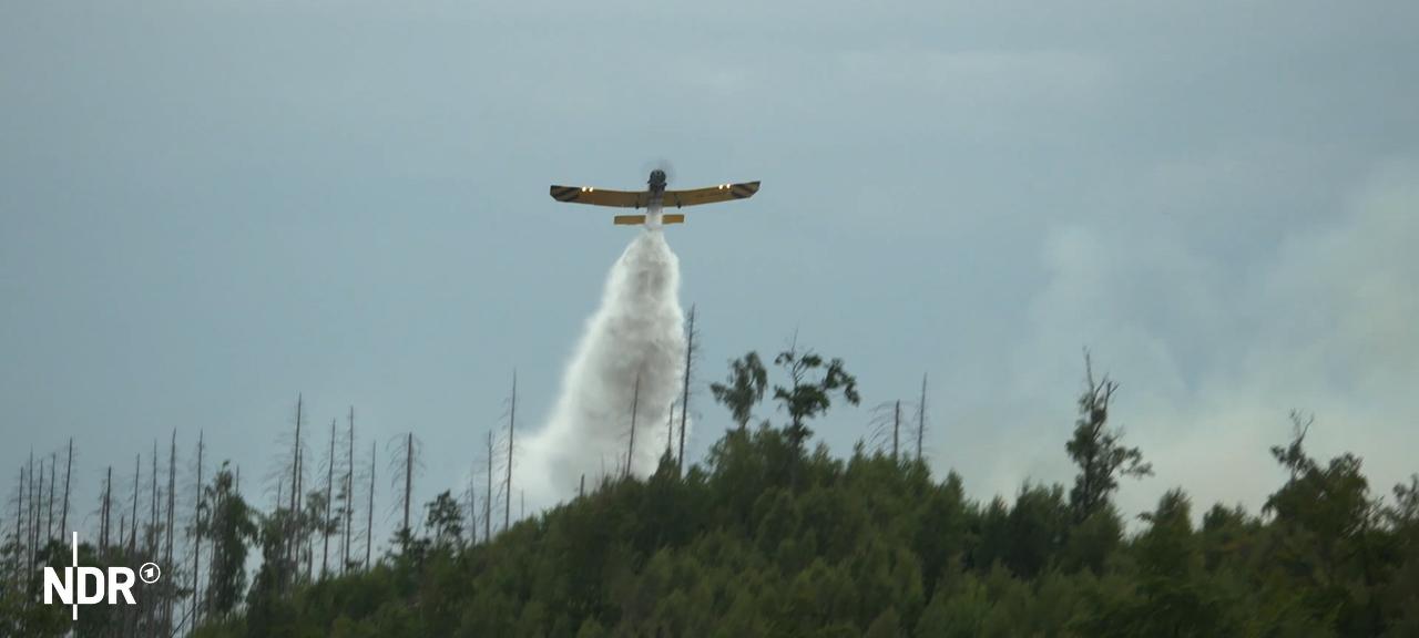 Ein Löschflugzeug fliegt über einem Waldbrand bei Goslar.