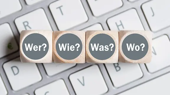 Würfel mit Fragewörtern auf einer Tastatur