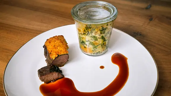 Rehrücken mit Bucheckernkruste, Soße und Semmelknödel im Weckglas auf einem Teller serviert