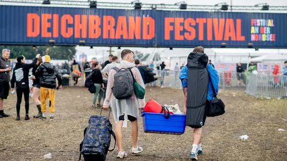 Zwei Festivalbesucher transportieren Zelte und Gepäck zum Zeltplatz des Deichbrandfestivals.
