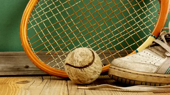 Tennisball, Schläger und Sportschuh sehen alt und dreckig aus.