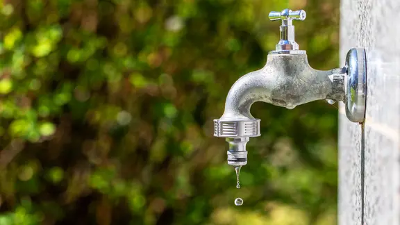 Ein tropfender Wasserhahn an einer Außenwand.
