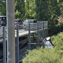 Am Parkhaus des AK barmbek in Hamburg ist ein Auto in einen Grünzu gestürzt. Einsatzkräfte der Feuerwehr sind rechts zu sehen. 