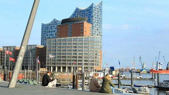 Nur wenige Menschen schlendern trotz Sonnenscheins während des Lockdowns über die Elbpromenade.