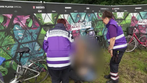 Zwei Frauen sprechen mit einer Person am Boden.