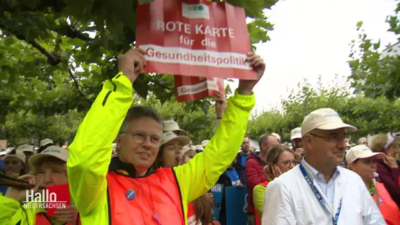 Protestierende, u.a. mit einem Schild: "Rote Karte für die Gesundheitspolitik".