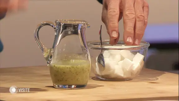 Ein Glas Fruchtsaft, daneben eine Schüssel mit Würfelzucker.