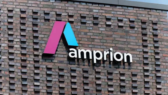 Das Firmenlogo des Übertragungsnetzbetreibers Amprion hängt an dem Gebäude der Hauptschaltleitung.