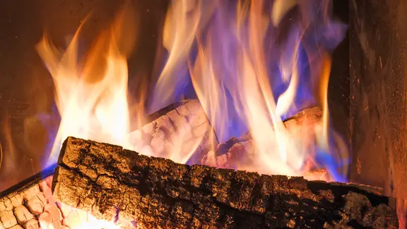 Offene Kamine ohne Tür oder Scheibe dürfen nur sehr eingeschränkt betrieben werden. | Colourbox Brennholz brennt in einem Kamin.