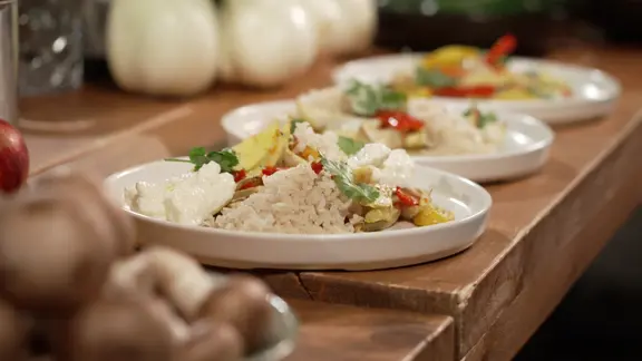 Drei Teller mit Ofengemüse und Vollkornreis auf einem Tisch.