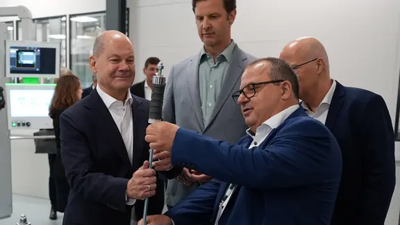 Eröffnung des Gigahubs für grüne Wasserstofftechnologie in Hamburg: Manager Jens Werner Schwarz (vorne, rechts) zeigt Bundeskanzler Olaf Scholz (links) einen Zuganker, der in einen sogenannten Stack eingeführt wird.