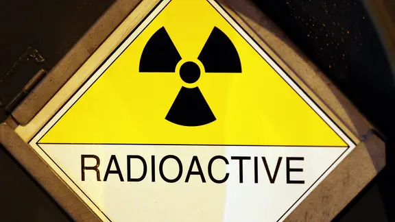 Ein Schild warnt an einem Castor-Transport mit der Aufschrift "radioactive" vor radioaktiver Strahlung.