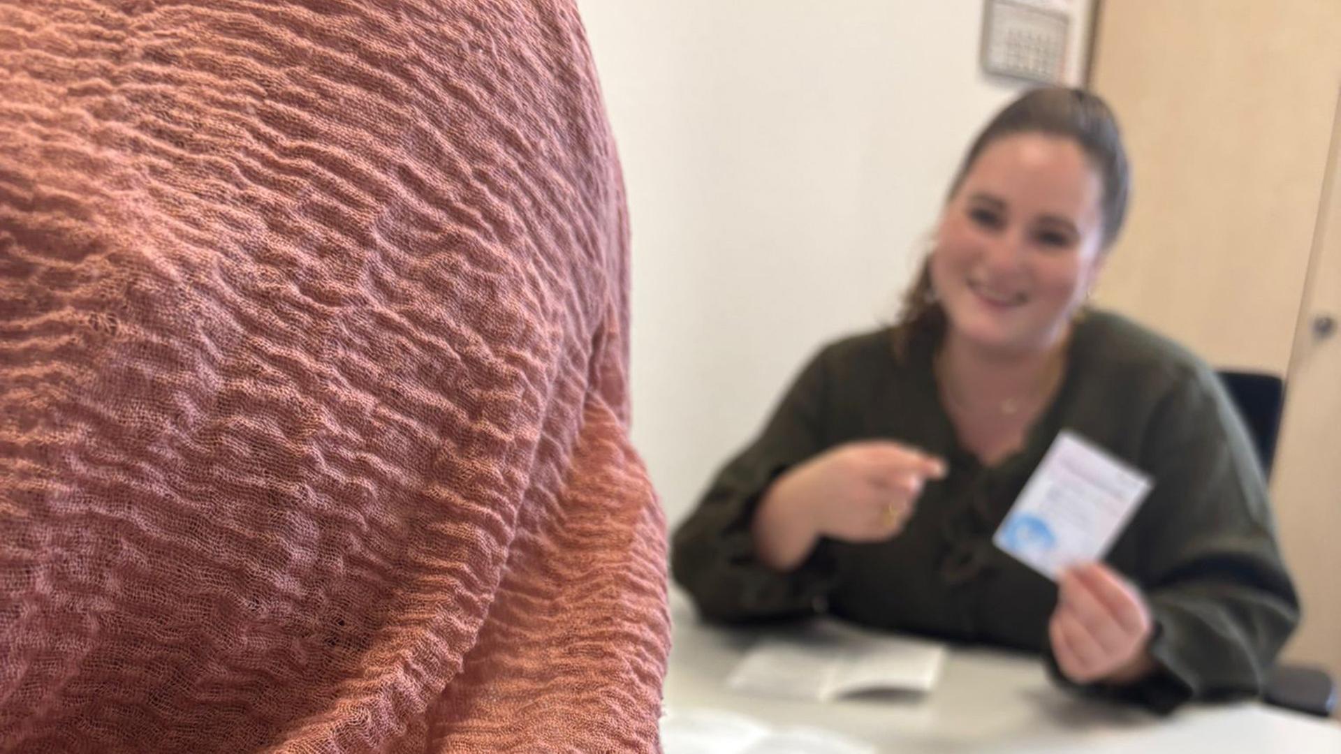 Die Beraterin sitzt einer Geflüchteten gegenüber und zeigt auf ein Stück Papier. | Caritas Osnabrück