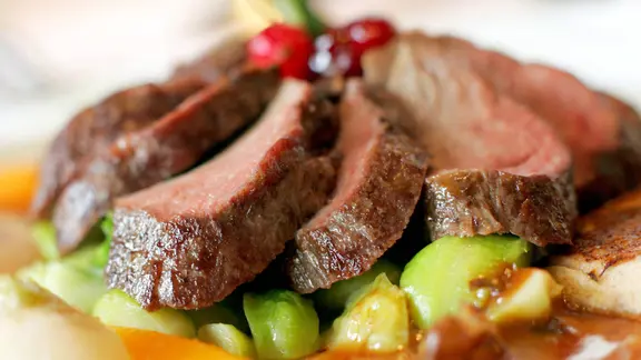 Rehbraten auf Gemüse serviert.