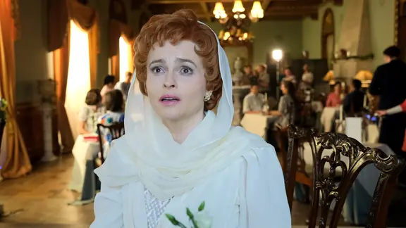 Frau steht in einem weißen Kleid mit Schleier in einem großen Saal am Filmset