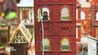 Eine Playmobil-Figur schaut aus einem offenen Fenster.