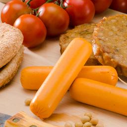 Fleischlose Würstchen und Bratlinge liegen auf einem Brett neben Tomaten und Brot.