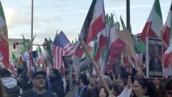 Zahlreiche Menschen mit iranischen oder US-amerikanischen Flaggen demonstrieren.