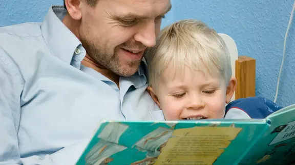 Vater liest seinem kleinen Sohn aus einem Kinderbuch vor.