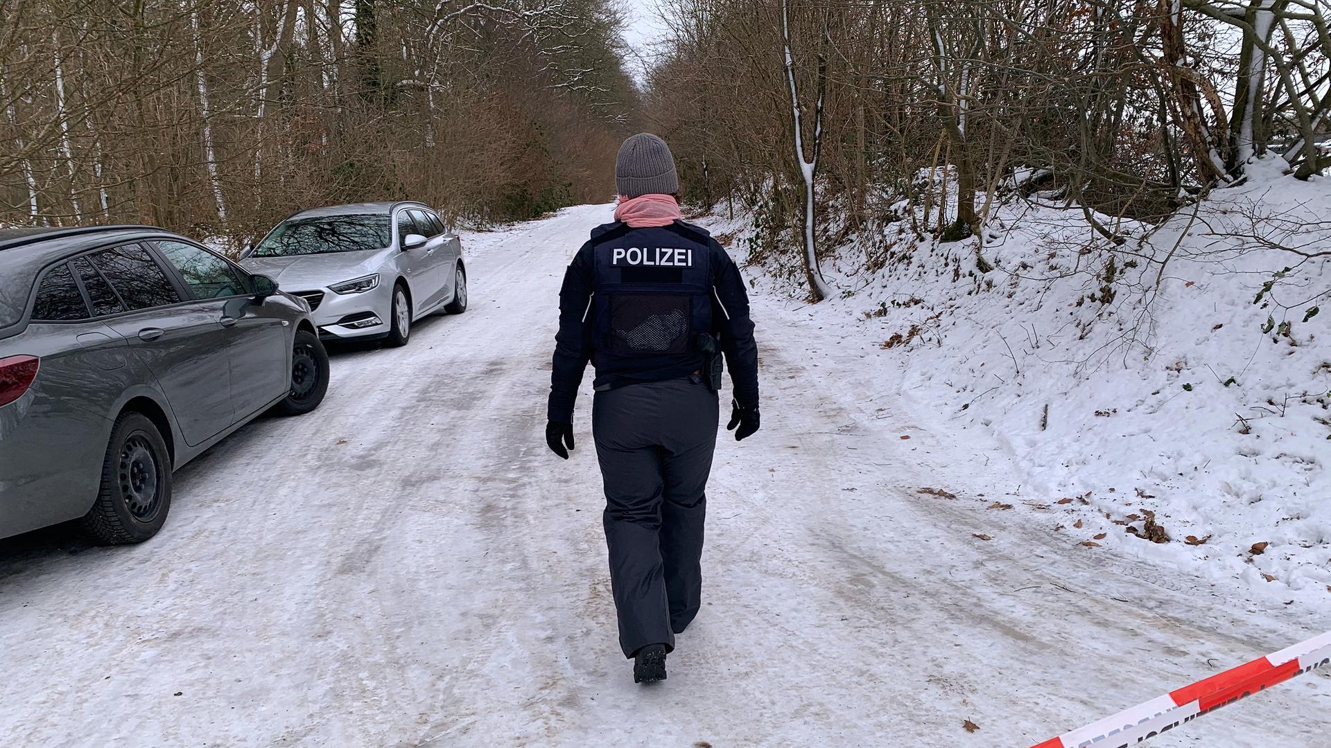 Eine Einsatzkraft der Polizei geht hinter einer Absperrung durch den Schnee. | LKA, Carola Jeschke