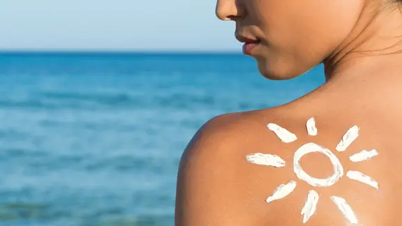 Frauenrücken mit einer Sonne aus Sonnenmilch.