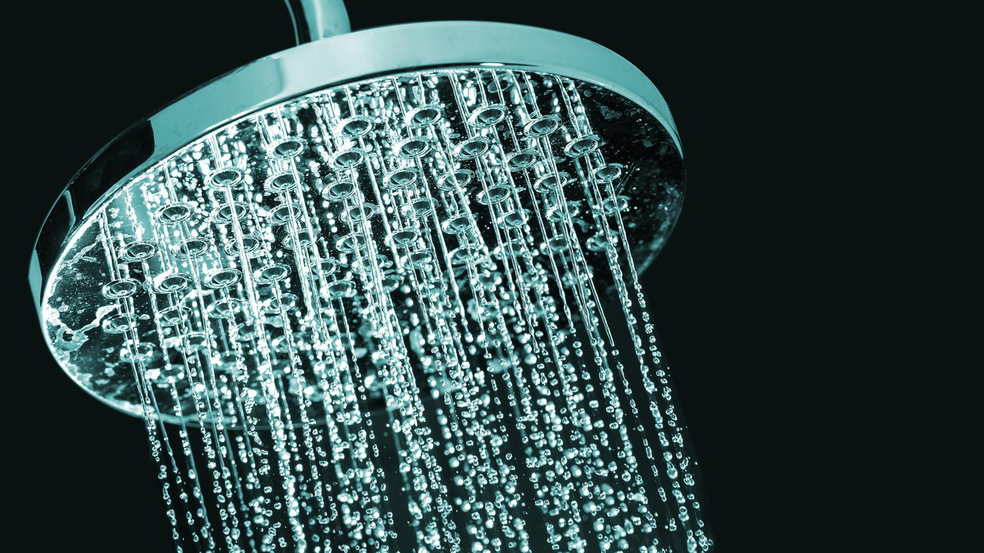 Aus einem Duschkopf kommt Wasser. | Colourbox
