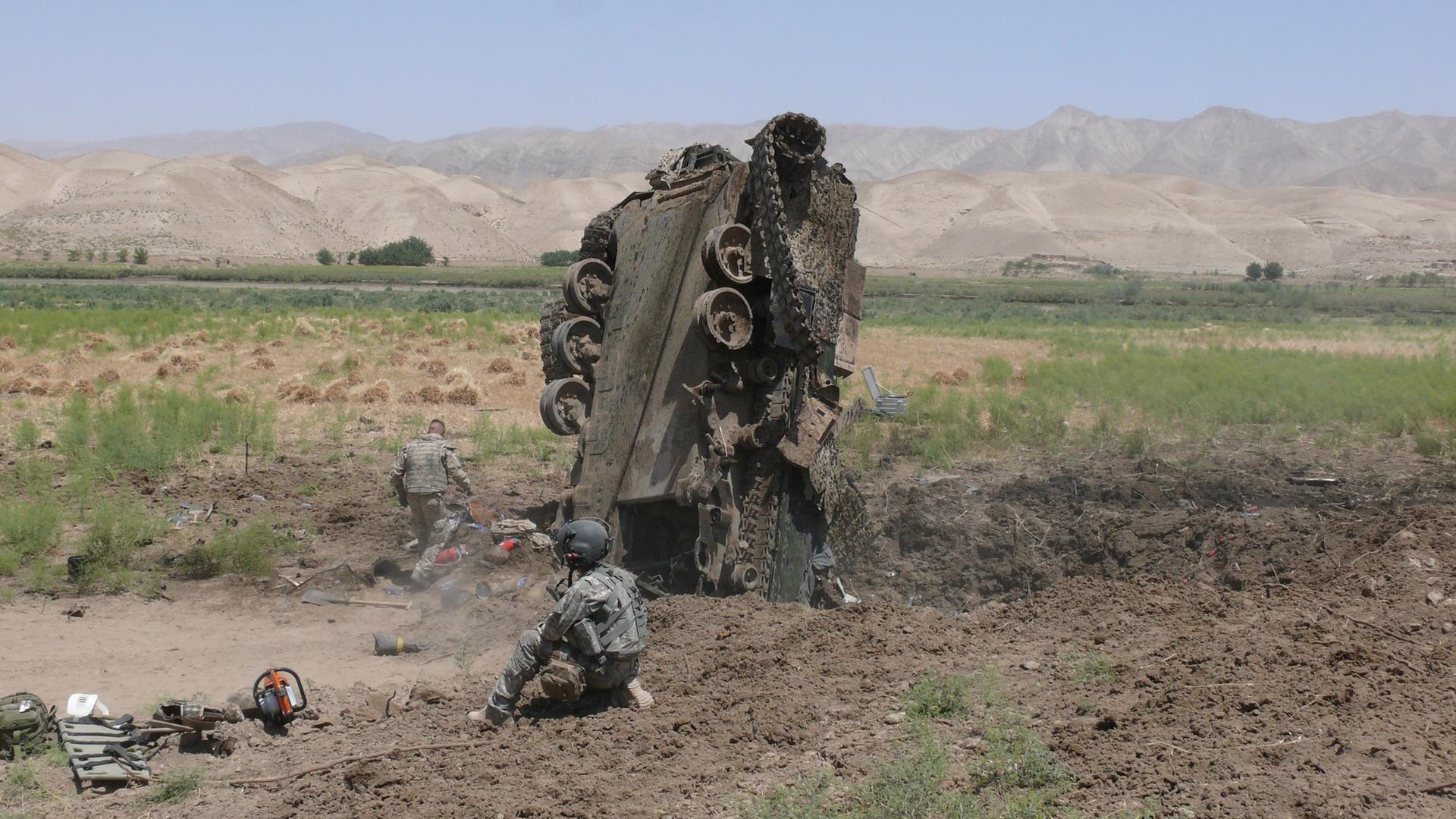 Ein Explosionskrater tut sich unter einem zerstörten Panzer in Afghanistan auf. | Stefan Paschetag