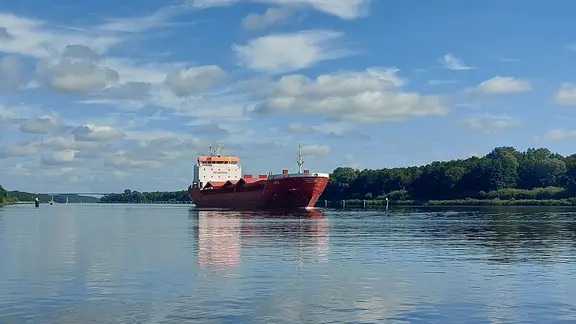 Ein rot-weißes Frachtschiff fährt über den Nord-Ostsee-Kanal.