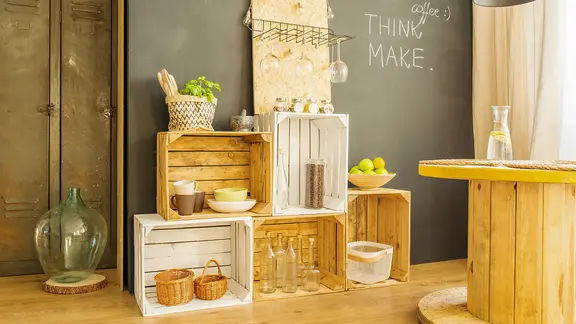 Ein Do-it-yourself-Regal aus Holzkisten, links ein Tisch aus einer alten Kabelrolle