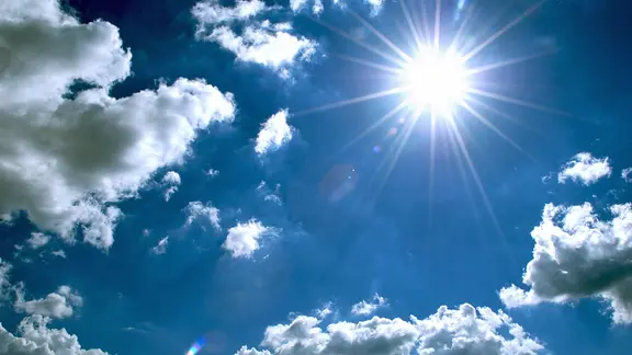 Die Sonne scheint an leicht bewölktem Himmel.