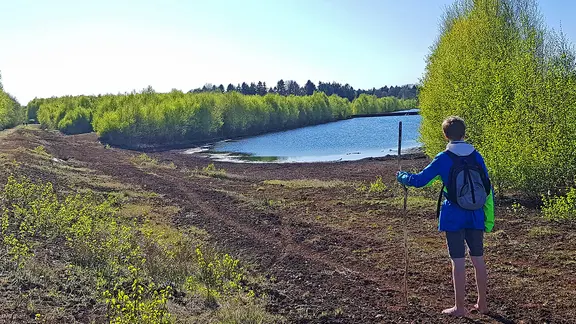 Ein Junge geht barfuß auf einem Weg im Huvenhoopsmoor