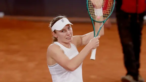 Eine Tennisspielerin hält den Schläger hoch. 