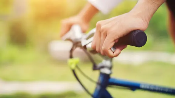 Blick auf die Hände eines Fahrradfahrers, der im Grünen radfährt