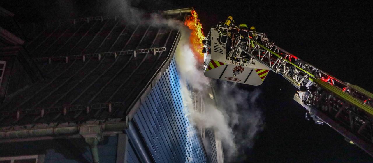 Feuerwehrleute bekämpfen über eine Drehleiter den Brand einer Holzkirche in Clausthal-Zellerfeld.