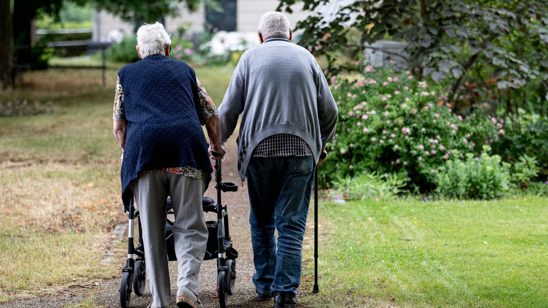 Zwei Senioren gehen mit Gehhilfen durch einen Garten. | picture alliance/dpa, Fabian Sommer