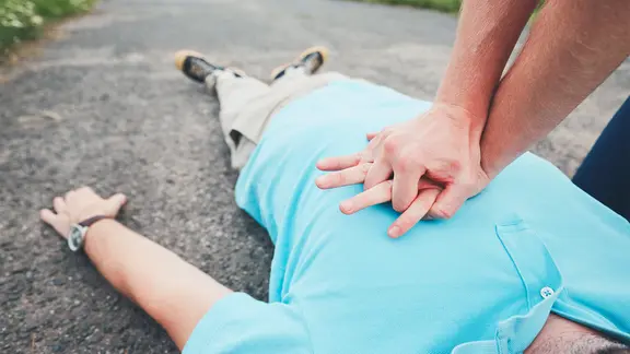 Herzdruckmassage an einem auf dem Boden liegenden Mann