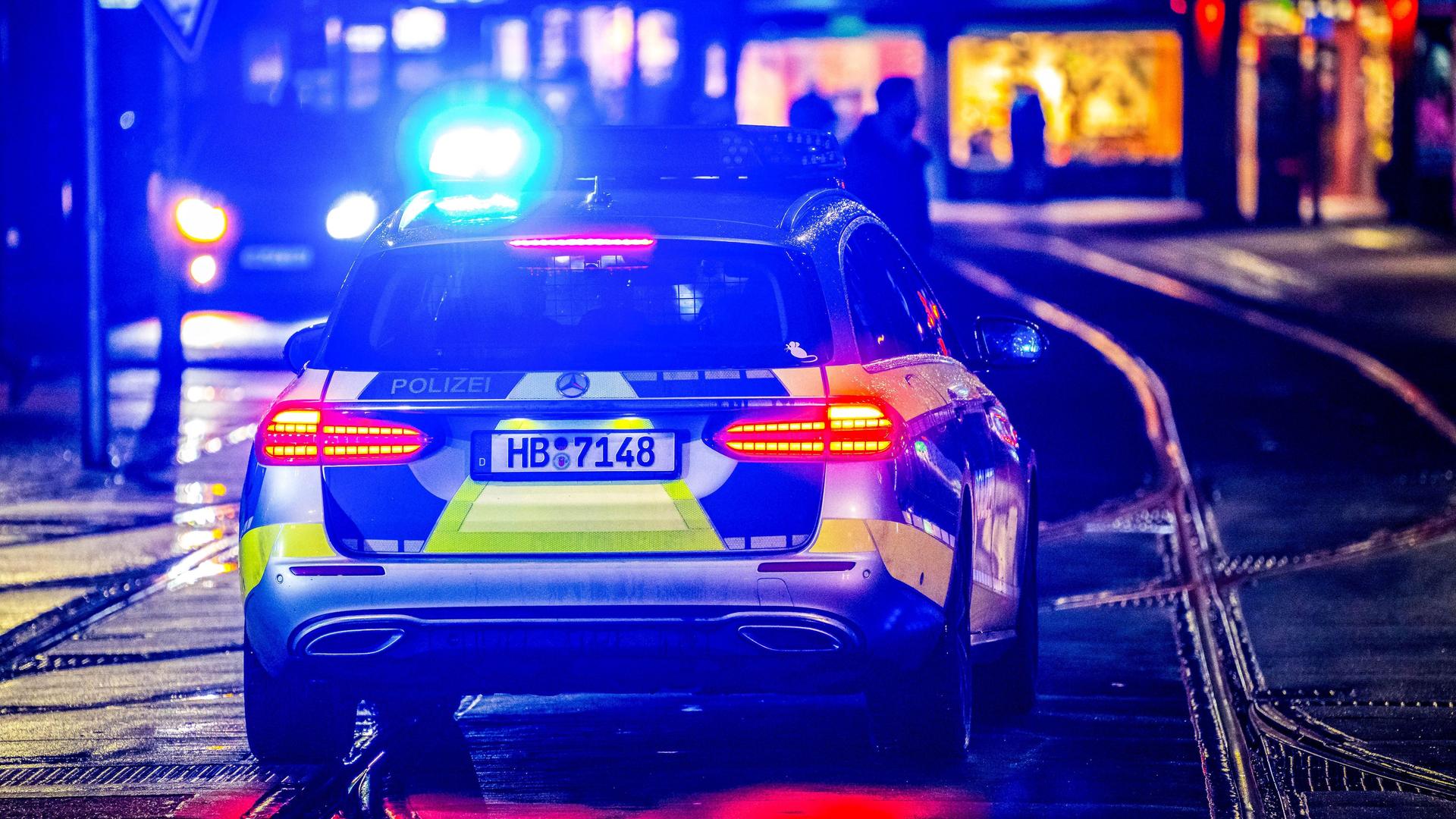 Ein Polizeiwagen fährt bei Nacht mit eingeschaltetem Blaulicht durch einen Straße in Bremen. | picture alliance/dpa , Sina Schuldt