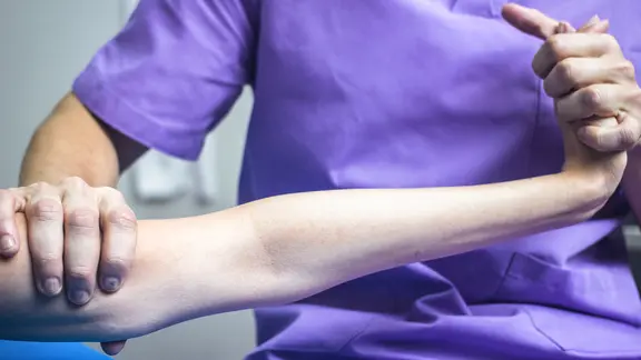 Ein Physiotherapeut bewegt einen Arm.