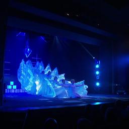 Kinder in weißen Kostümen in schwachem blauben Licht auf einer Bühne.