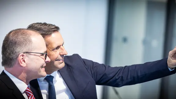 Zwei Männer machen ein Selfie mit einer Einmalkamera.