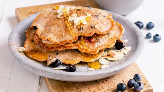 Ein Stapel Mandel-Pfannkuchen mit Blaubeeren liegt auf dem Teller.